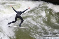 Ein Surfer surft auf der Eisbachwelle im Englischen Garten in München 