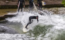 Ein Surfer surft auf der Eisbachwelle im Englischen Garten in München